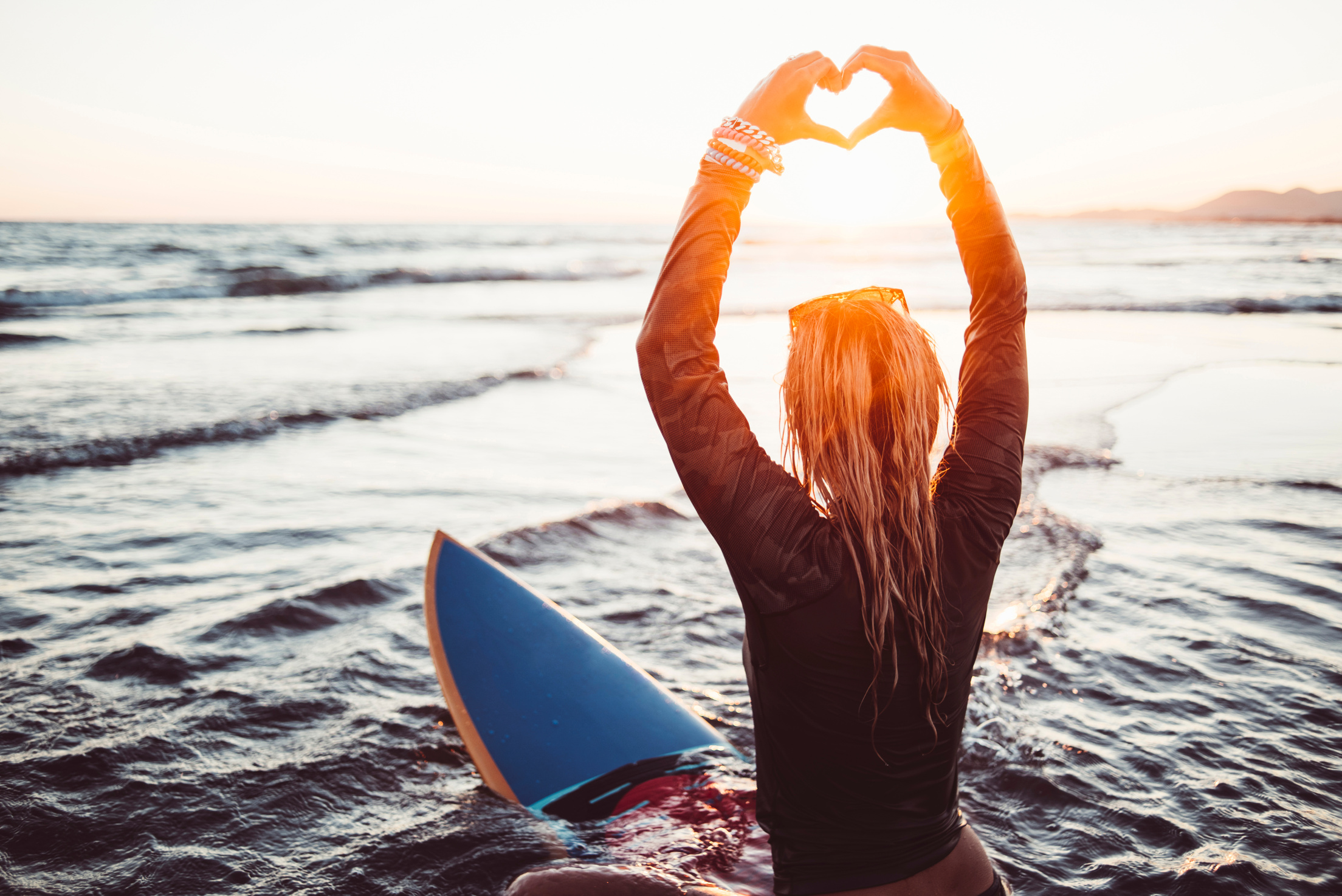 Female surfer showing love